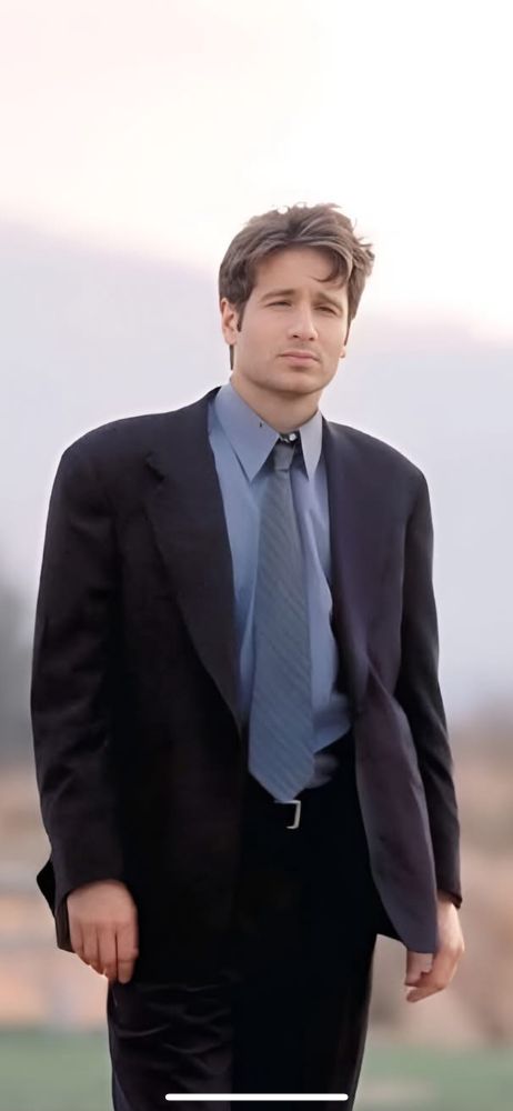 Young David Duchovny as FBI Agent Fox Mulder dressed in a dark suit with a blue dress shirt and grayish tie