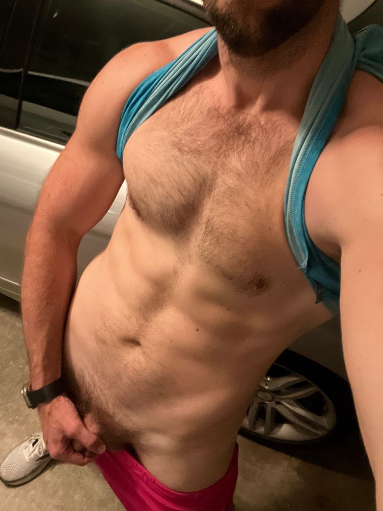 Semi naked, my soft cock in hand and blue vest pulled over my head like a harness. My abs and hairy chest on display