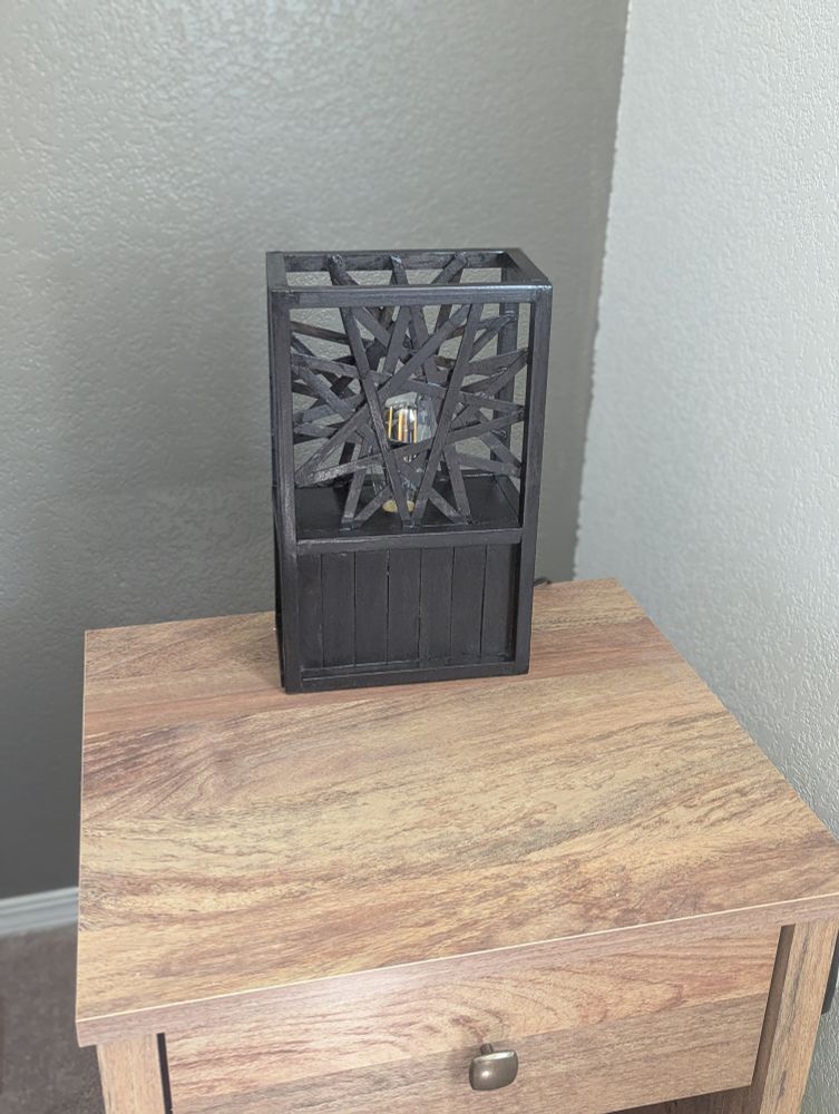 A wooden bedside lamp stained dark with a 12 pointed star design