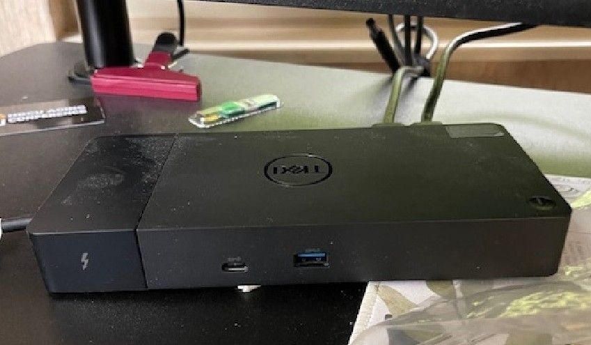Dell Thunderbolt dock sitting on a desk. Behind it, at the back of the desk, the power cord is clearly unplugged and about to fall off the desk.