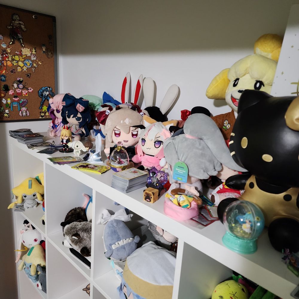 My plush shelf. There are many plushes. There are also unorganized trading cards about and things are in disorder. Jirachi sleeps here. 