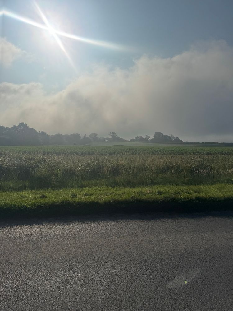 A pretty boring photo of some road with a cloud in the background.