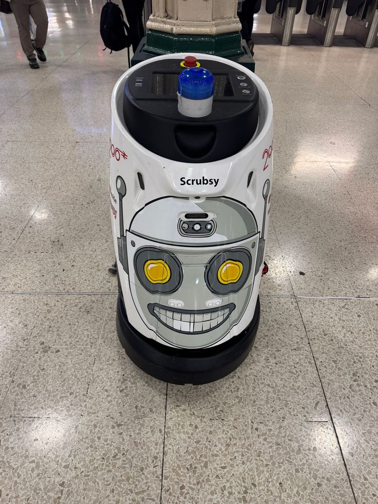 A horrifying sticker of a robot face on a floor-cleaning robot. 