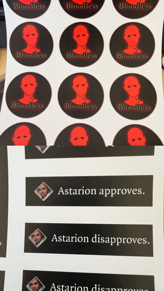 Sheets of stickers in various designs. One is the “Bloodless” icon from Baldur’s Gate 3, and the other two are versions of the Astarion approves or disapproves notifications with my silly little cosplay replacing the image of Astarion’s face.