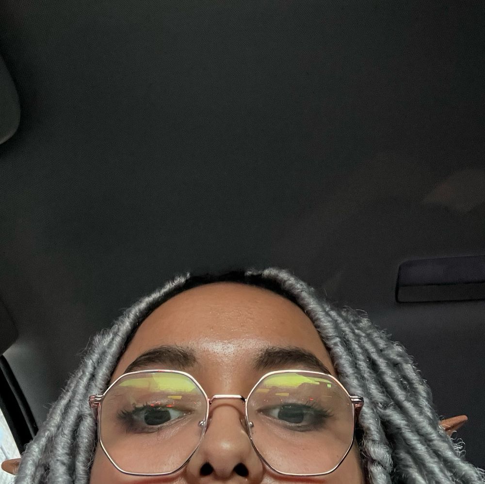 Selfie of me, peeking from the bottom of the screen with elf ears and gray locs