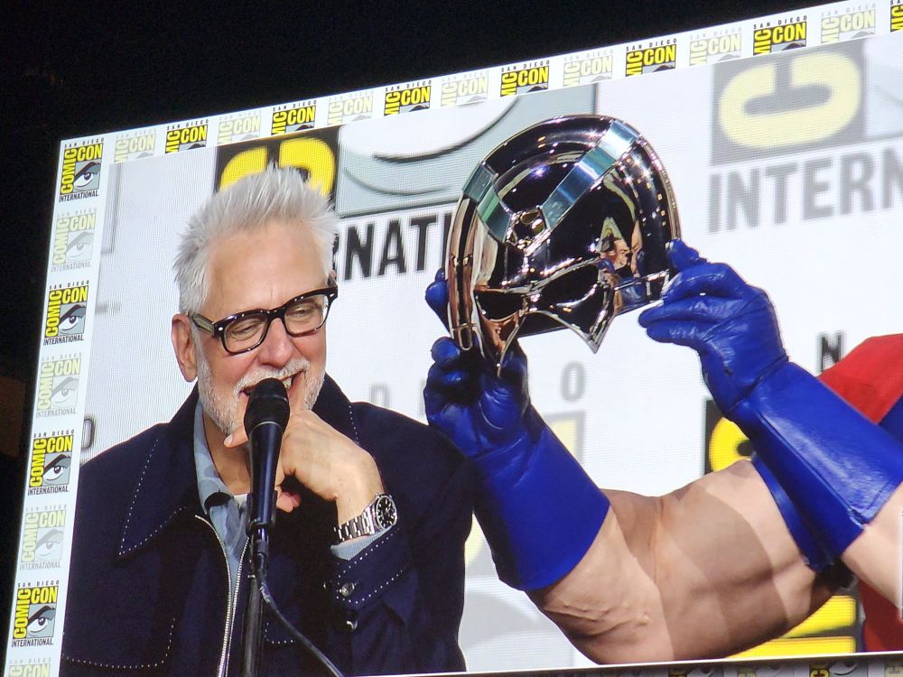 John Cena holds up his helmet next to James Gunn to tease him about the You Can't See Me jokes