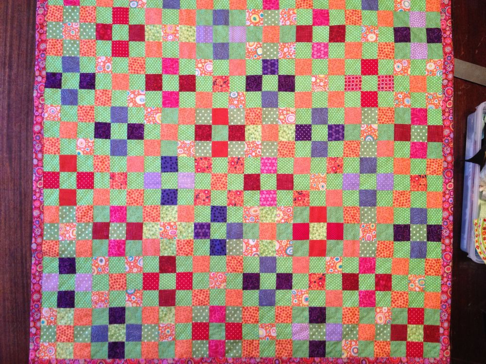 Nine patch quilt in green, purple, orange, red and pink. 