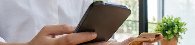 A person holding a smartphone and a credit card