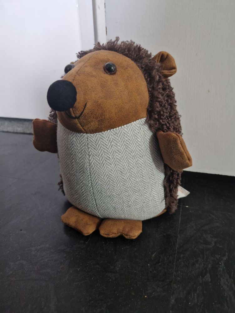 Photo of a cuddly hedgehog doorstop smiling at the camera.