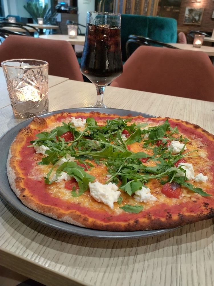 [ID: An image of a pizza with cherry tomatoes, mozzarella cheese and rucola on top. End of ID]