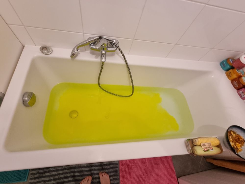 Volle Wanne, gelber, fast fluoreszierender Badezusatz im Auflösen befindlich