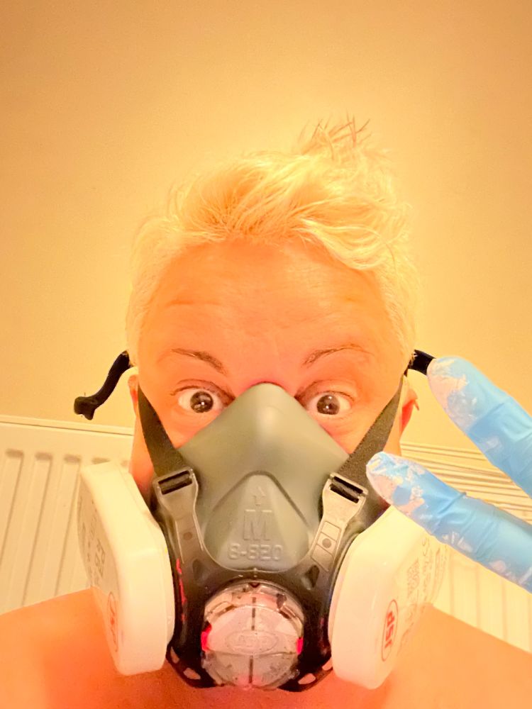 Cristina with blonde hair and a filter mask with blue plastic gloves 