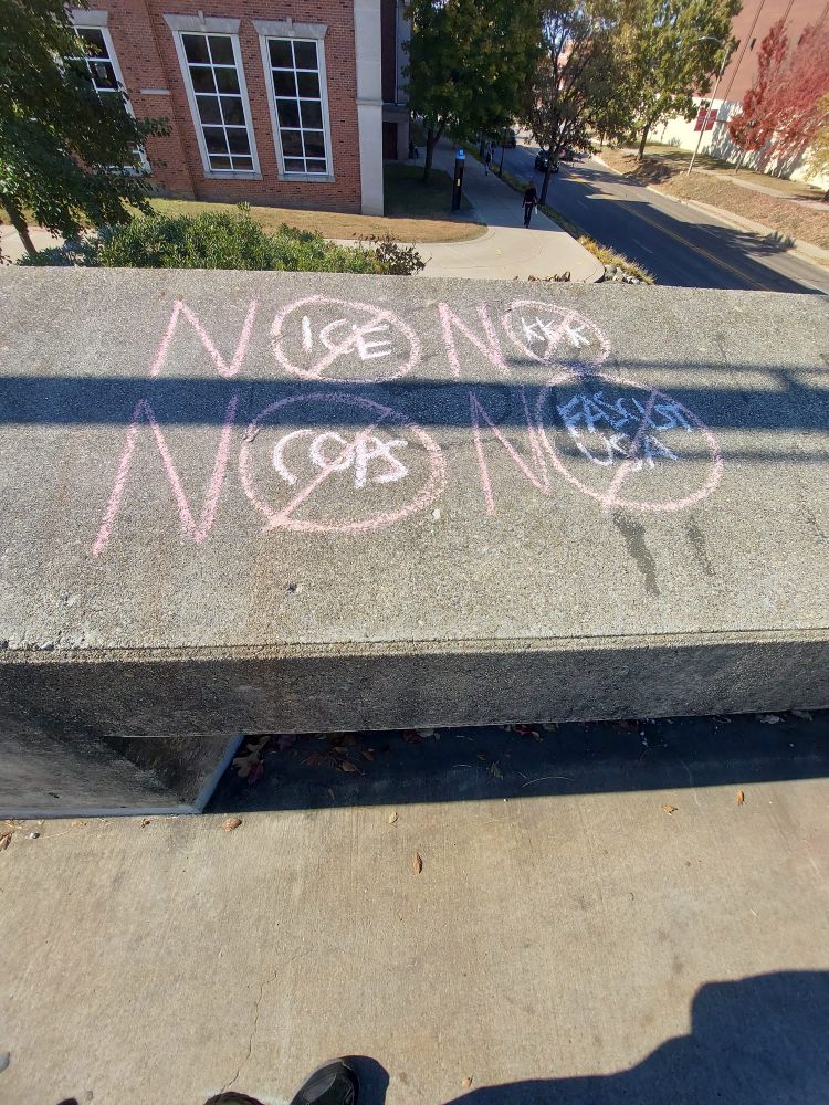 Chalk on cement guardrails that reads: No Ice No KK No Cops No Fascist USA