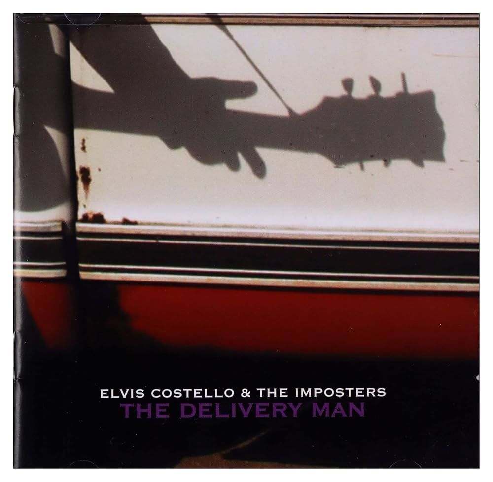 The album cover for Elvis Costello and the Imposters The Delivery Man album. There is a shadow on a red and white Chevy C10 of a man (presumably EC)playing guitar. 