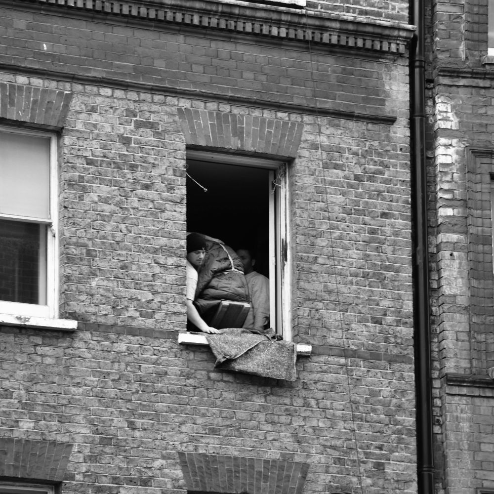 If you can’t transport large objects down the stairs in a block of flats, you have to squeeze them through a window. Look out below because that looks heavy. Is it a piano? 