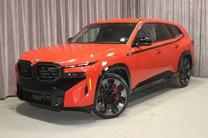A bright orange BMW XM SUV with a huge snout shaped grille