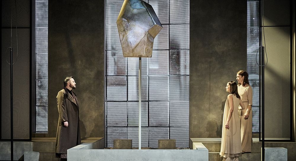 Antiochus fait face à Bérénice et Phénice. Une sorte de cristal trône au sommet d'un mince poteau au milieu de la scène et des vitraux rectangulaires tapissent le fond.