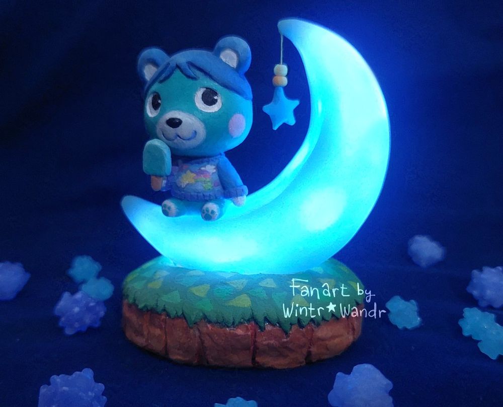 The same Bluebear sculpture in the previous image. The lights in the photo are dimmed and the crescent-moon chair is lit up and glowing with a blue light.