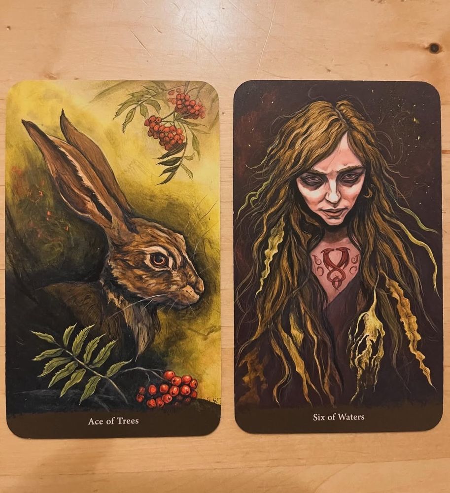 Two tarot cards, one showing a hare with rowan berries, one a wild looking woman