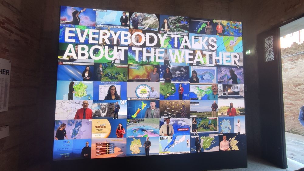 Eine riesige Wand mit vielen verschiedenen Videos, alle von Wetterleuten aus aller Welt, mit dem Schriftzug "Everybody Talks about the weather"
