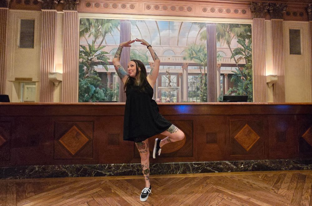 Chrystal doing a ballerina pose at the front desk of the Biltmore Hotel.