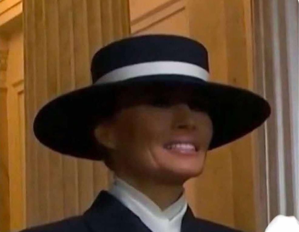 Melania Trump with her eyes hidden by her hat, looking surprisingly similar to Jim Carrey in The Mask.