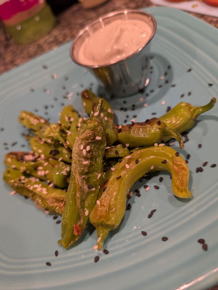 Blistered home grown Shishito Peppers with roasted sesame oil, and black and white sesame seals.