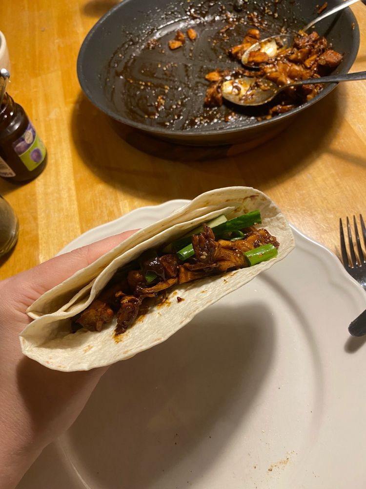 Gefalteter Pfannkuchen mit Füllung und im Hintergrund die Pfanne mit dem Jackfruit-Entenfleisch