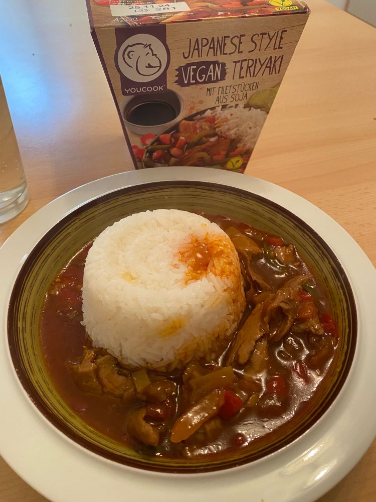 „Japanese style vegan Teriyaki“ mit Filetstücken aus Soja von YouCook, angerichtet auf einem Teller, dahinter die Originalverpackung 