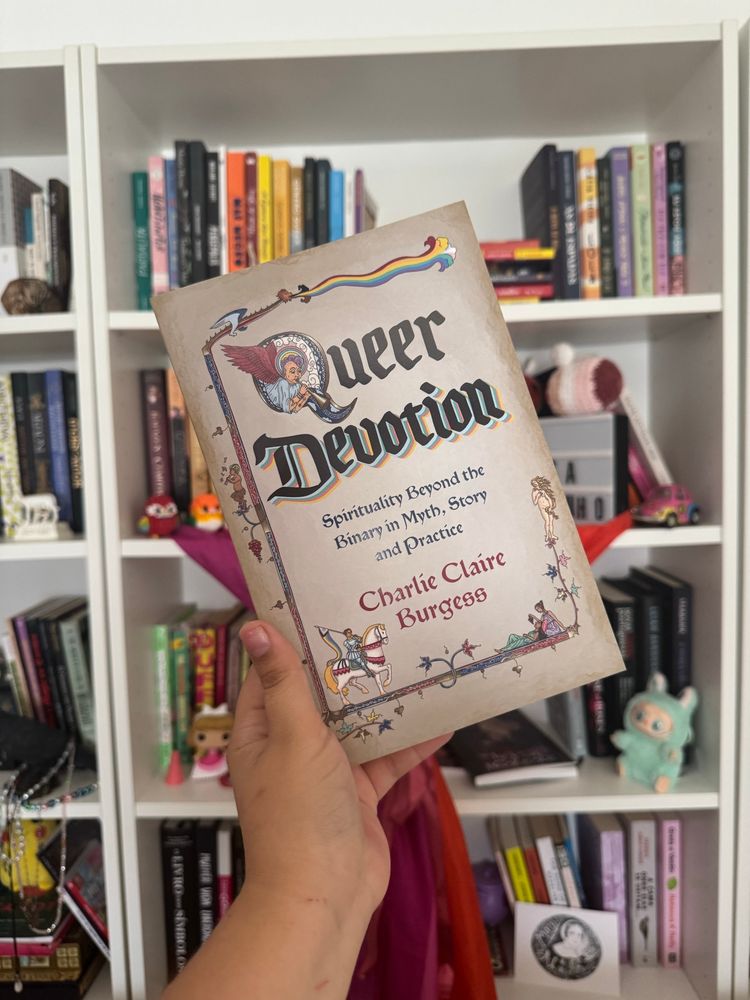 A book titled “Queer Devotion” in front of a shelf