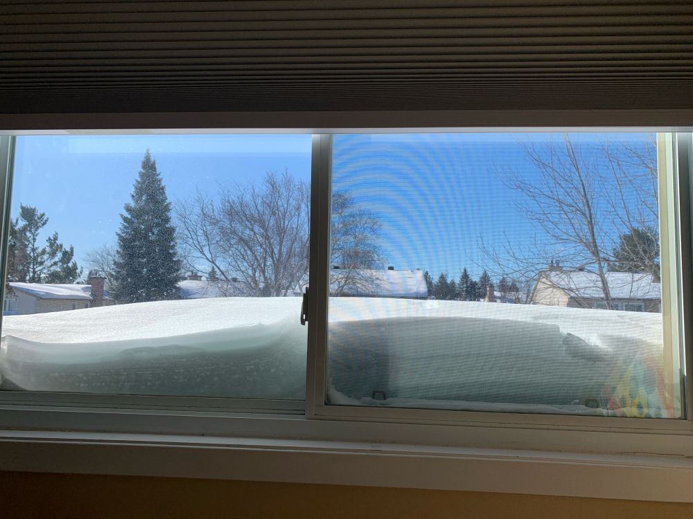 Looking out a second story window at the snow on the roof, which is above the window sill