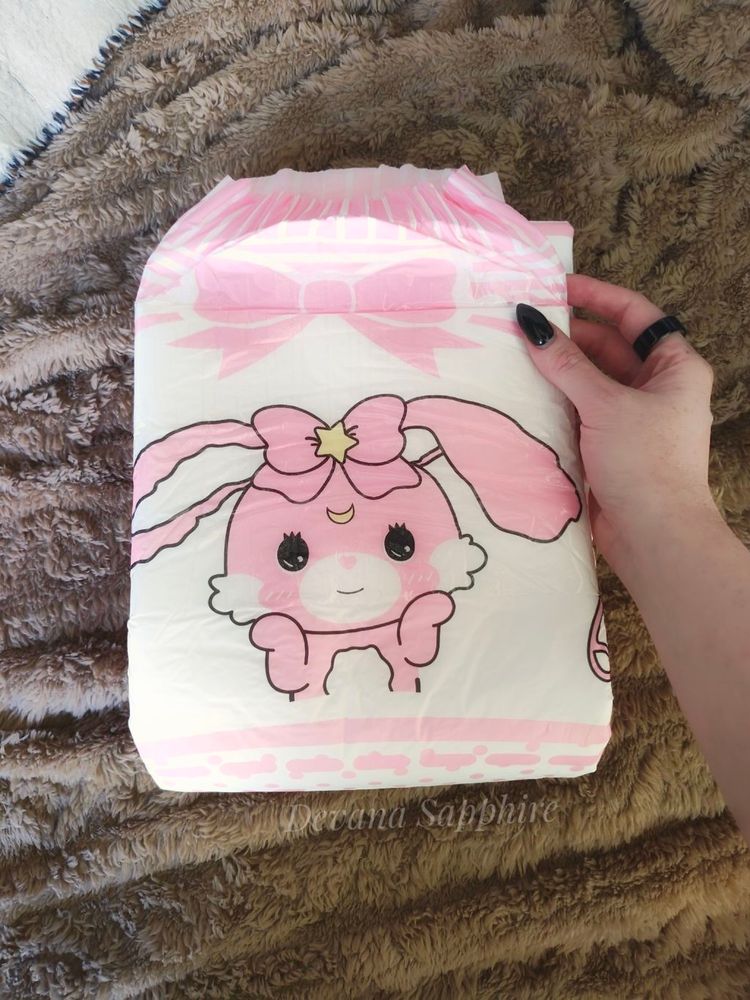 My hand holding a pink bunny diaper.