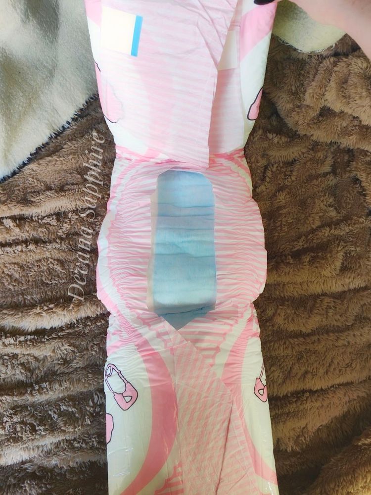 My hand holding a pink bunny diaper. I've opened the front and back so the absorbent, blue padding can be easily seen.