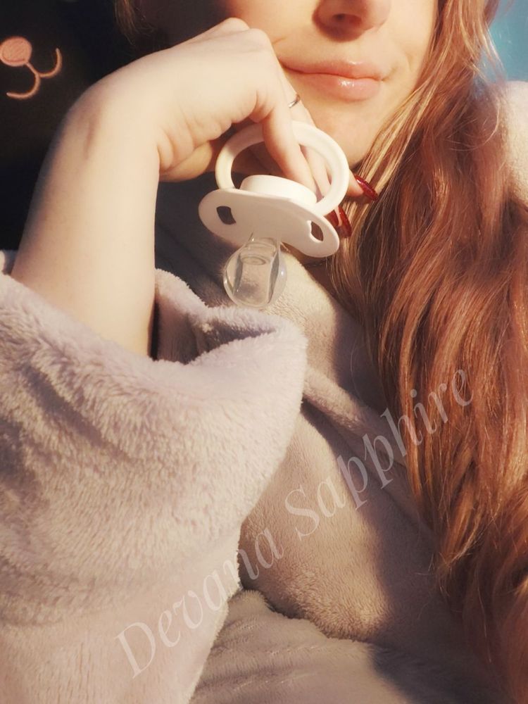 Me smiling and playfully holding a pacifier between my fingers. 