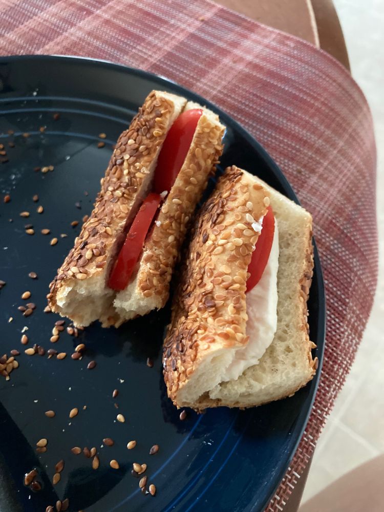 Turkish simit sandwiches made with feta cheese and tomatoes on the top of a dark blue plate