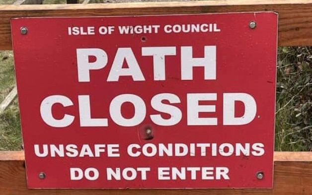A photo of a red sign that says "Path Closed, Unsafe Conditions, Do not enter"