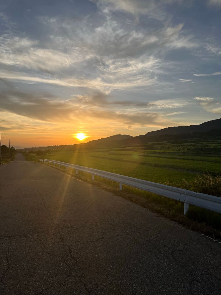 Sun setting behind foothills in Aizu-Bandai National Park, Fukushima Prefecture, Japan. Rice fields by the side of this little used farming road, ideal for cycling at dusk. 