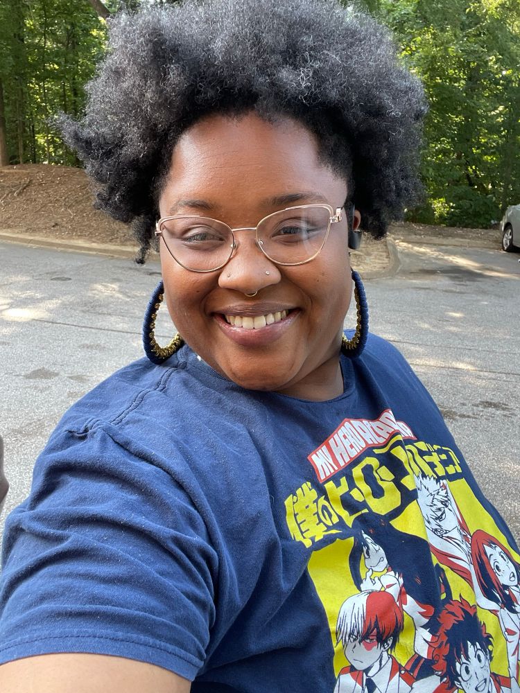 K in navy blue MHA shirt smiling with hair in pineapple 