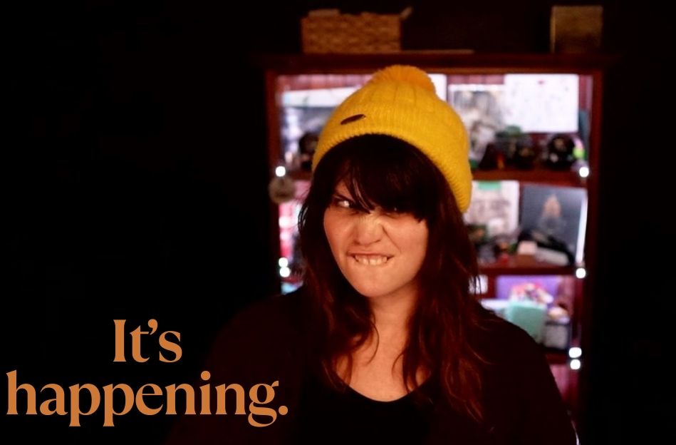 Thumbnail of me making a face with a yellow beanie with written "it's happening" in yellow letters