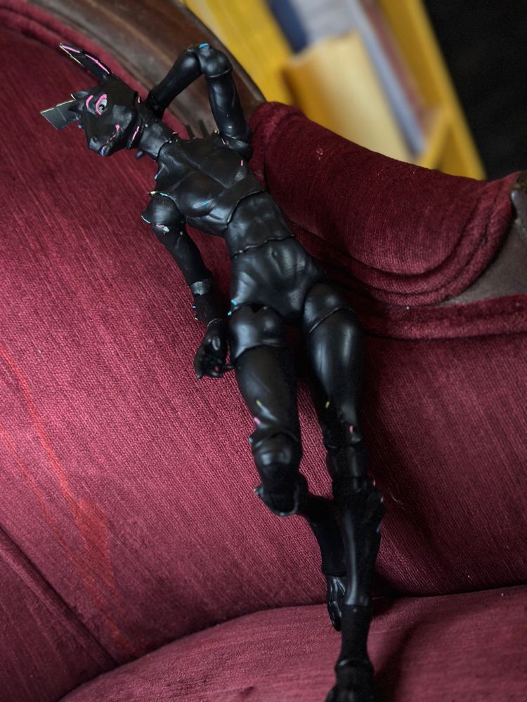 Cay leaning back against a velvet couch looking saucy