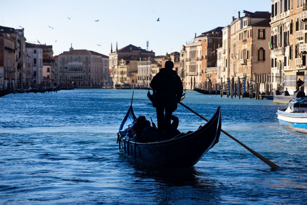 A group of tourists enjoy their gondola ride along the Gran Canal in Venice. It is early and the city hasn't quite woken up, allowing them to enjoy their ride in relative peace.
