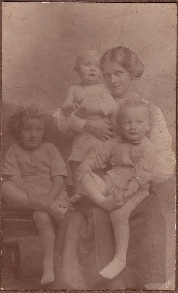 Sepia photo from around 1918 of young woman seated, with her three young children