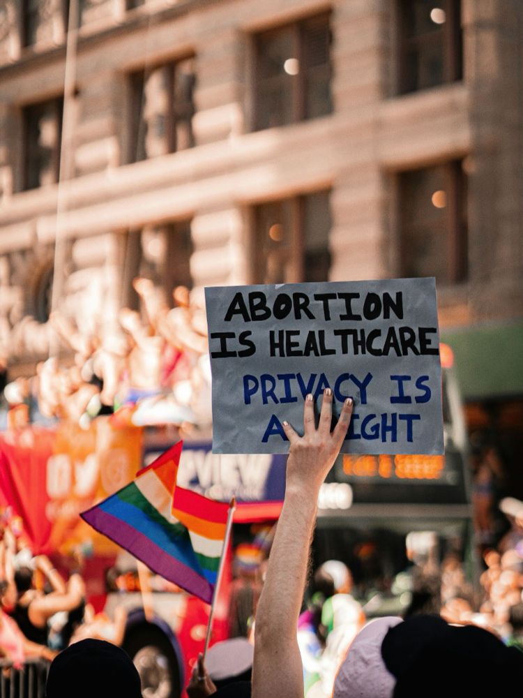 A person holds up a protest sign: Abortion is healthcare. Privacy is a right.