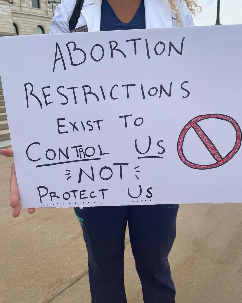 Medical student holding sign that says: Abortion restrictions exist to control us, not protect us.