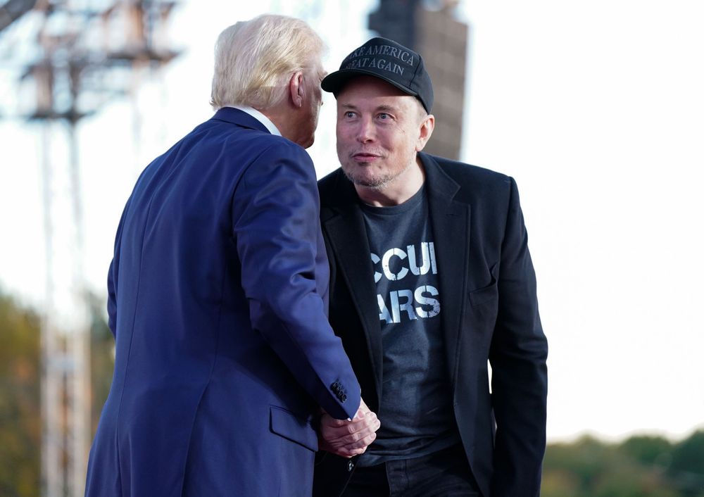 Photograph of a bug eyed Elon Musk shaking hands with the orange emperor.