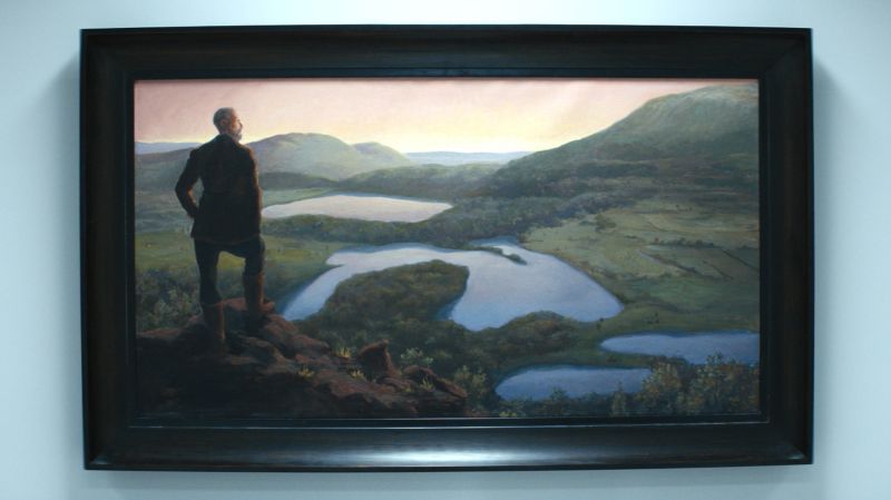 A painting from the Lumon offices titled, “Kier Invites You to Drink of His Water”.

The painting depicts Lumon Industries founder Kier Eagan atop a cliff overlooking what appears to be a valley that includes the Great Lakes.