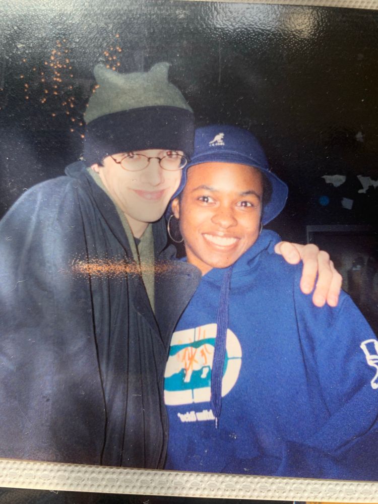 Young white man with black coat, black and green winter hat and glasses with arm around young black woman with navy blue kangol bucket hat, navy blue ekco hoodie and big silver hoop earrings at the Wallace Civic Center,Fitchburg, MA.