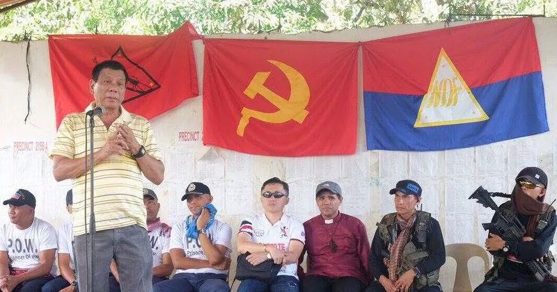 Davao City Mayor Rodrigo Duterte meeting with New People’s Army rebels. Flags of the Communist Party/National Democratic Front are behind him and armed men