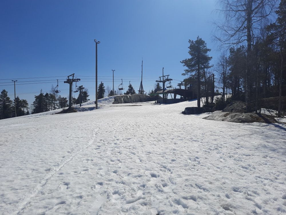 Lunta laskettelurinteessä Vuokatinvaaran päällä. Taustalla näkyy hiihtohissi. Taivas on sininen ja ilma kirkas.