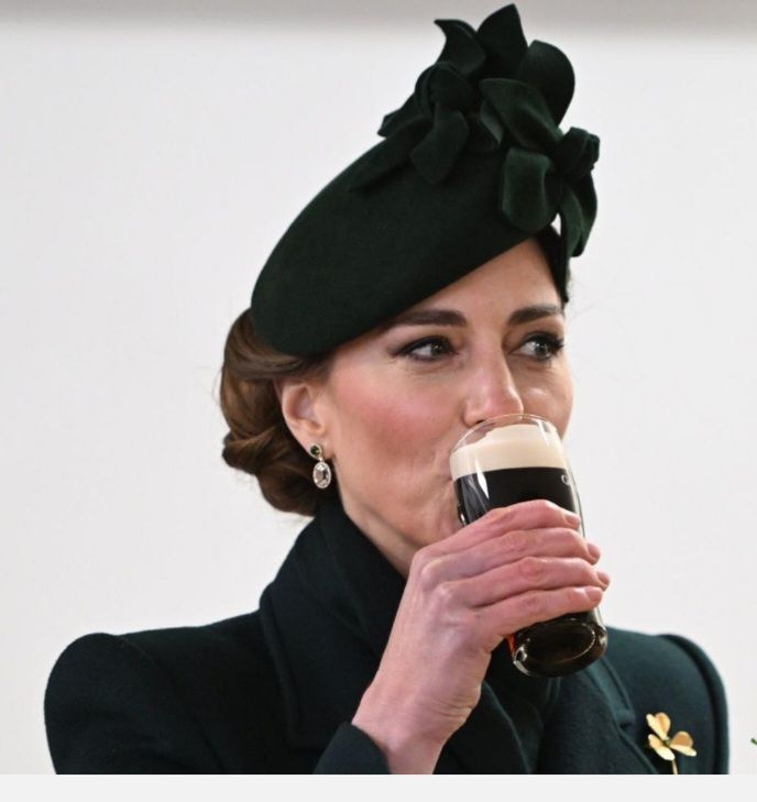 Princess of Wales dressed in green outfit with shiny shamrock badge drinks Guinness on St Patrick's Day. 